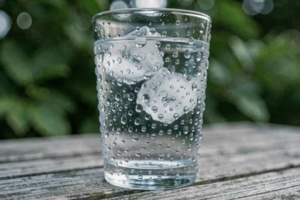 Gouttelettes de condensation sur un verre d'eau froide posé sur une table en bois, illustrant le phénomène de condensation de la vapeur d'eau