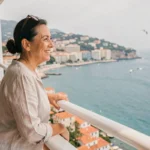 Femme souriante sur le pont d'un bateau de croisière au départ de Nice avec vue sur la côte méditerranéenne