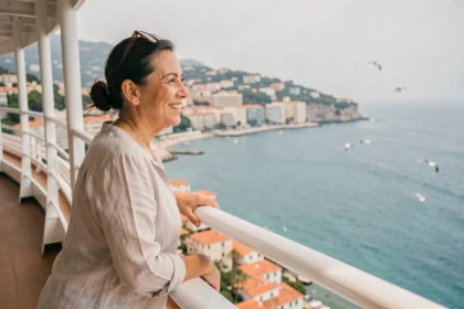 Femme souriante sur le pont d'un bateau de croisière au départ de Nice avec vue sur la côte méditerranéenne
