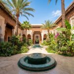 Cour intérieure somptueuse d'un palace marocain à Marrakech avec fontaines en mosaïque, jardins luxuriants et architecture andalouse ornementale
