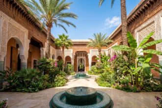Cour intérieure somptueuse d'un palace marocain à Marrakech avec fontaines en mosaïque, jardins luxuriants et architecture andalouse ornementale