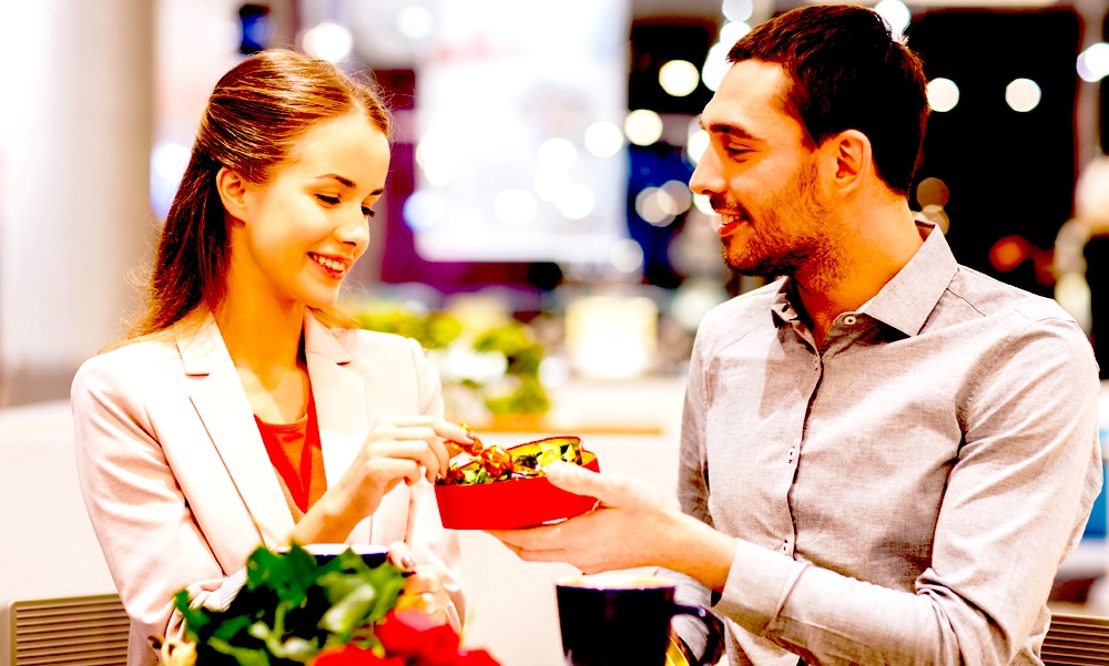 happy couple with present and flowers in mall