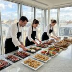 Équipe de traiteur professionnel dressant un buffet d'entreprise élégant dans une salle de réunion parisienne moderne